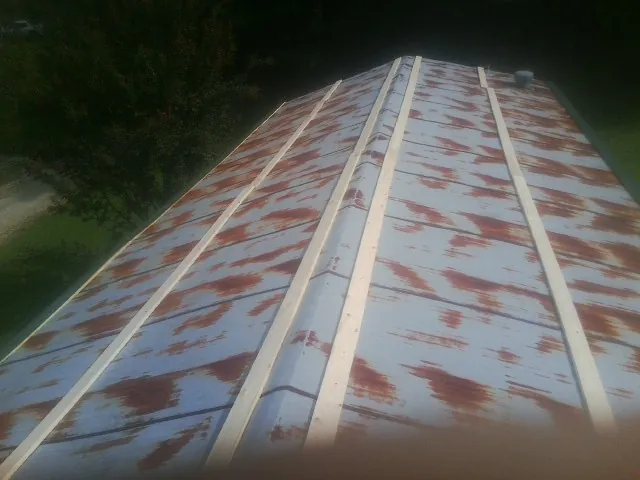 Rusted metal roof panels with new wood purlins before replacement — Storm Damage Roof Repair in Shelter Island Heights by Roofing Brothers