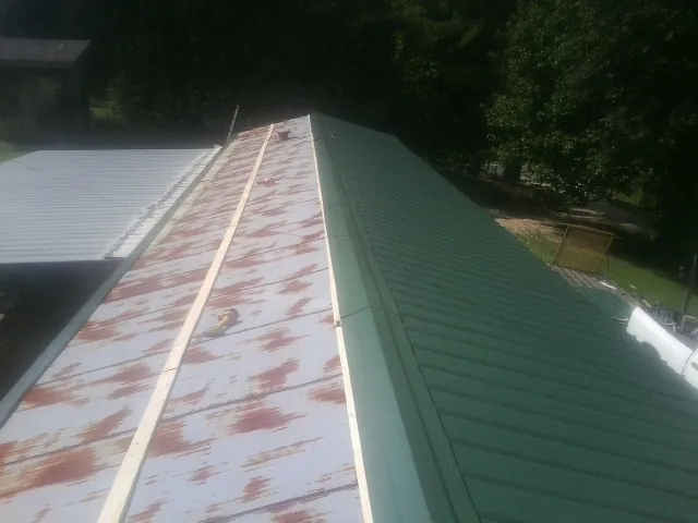 Old rusted panels beside newly installed green metal roofing — Wind Damage Roof Repair by Roofing Brothers in Shelter Island Heights