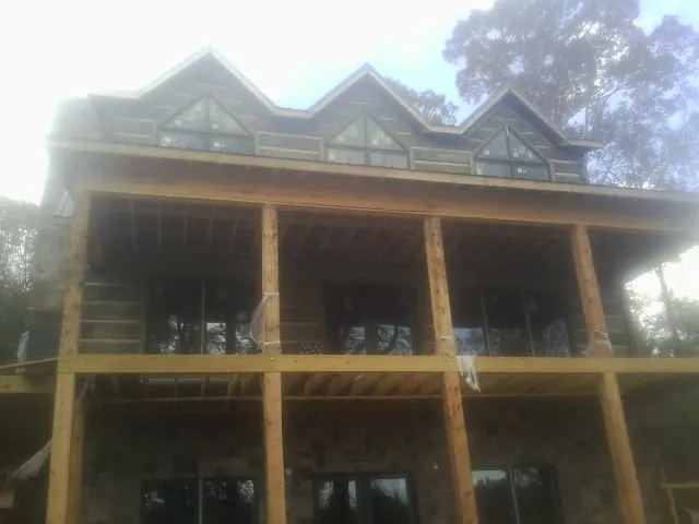Dormers and porch framing on a large log home under construction — Roof Coating work by our crew in Shelter Island Heights