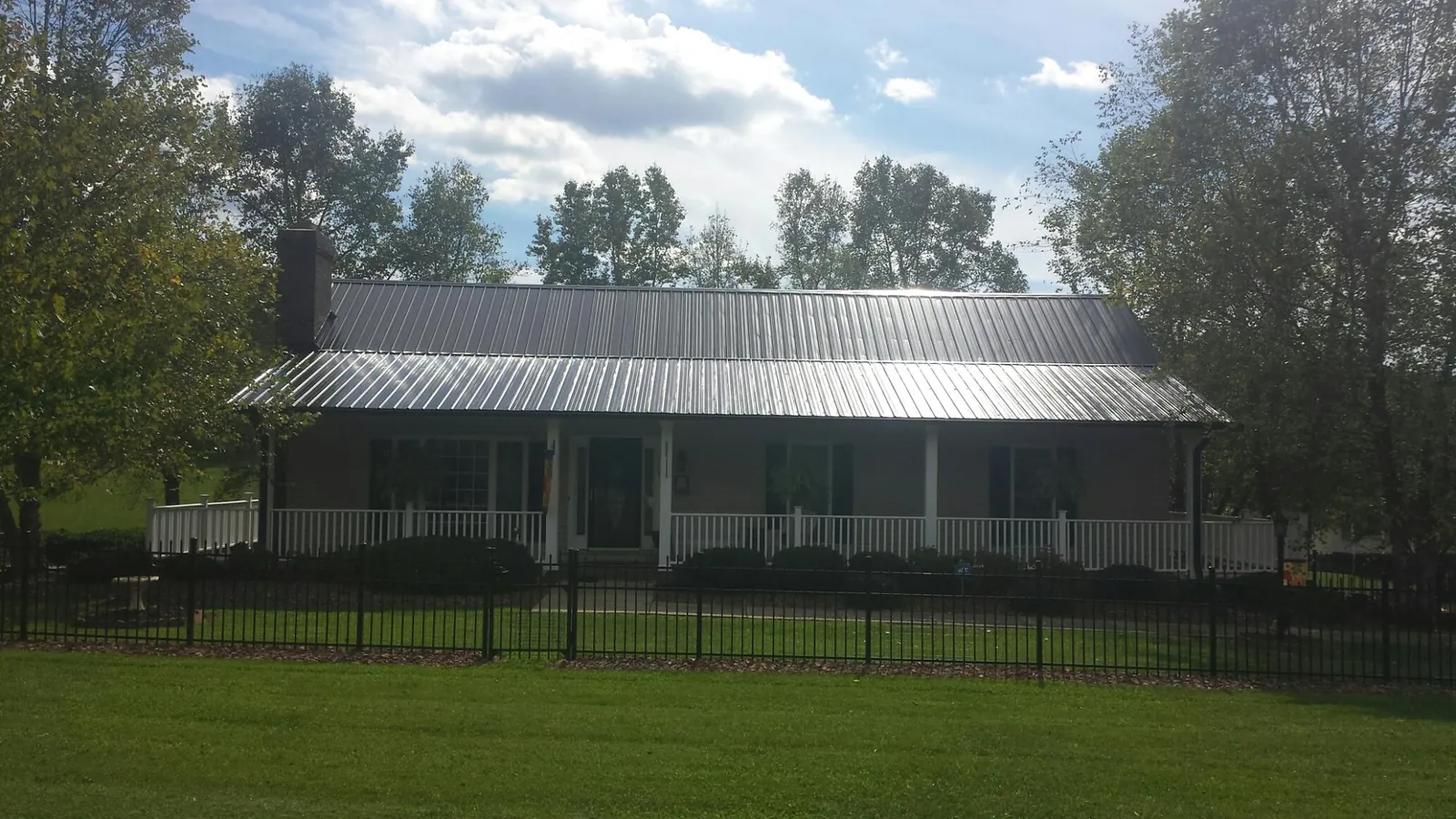 Gray metal roof on a brick ranch with a full width front porch — Gutter Guard Installation work by our crew in Shelter Island Heights