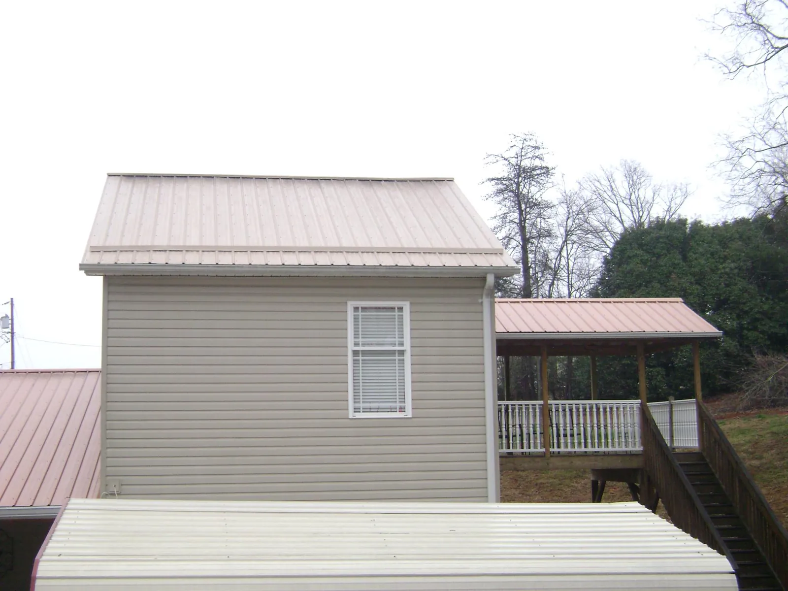 Tan metal roofs on a two story addition and attached porch, from a Roof Replacement job in Shelter Island Heights