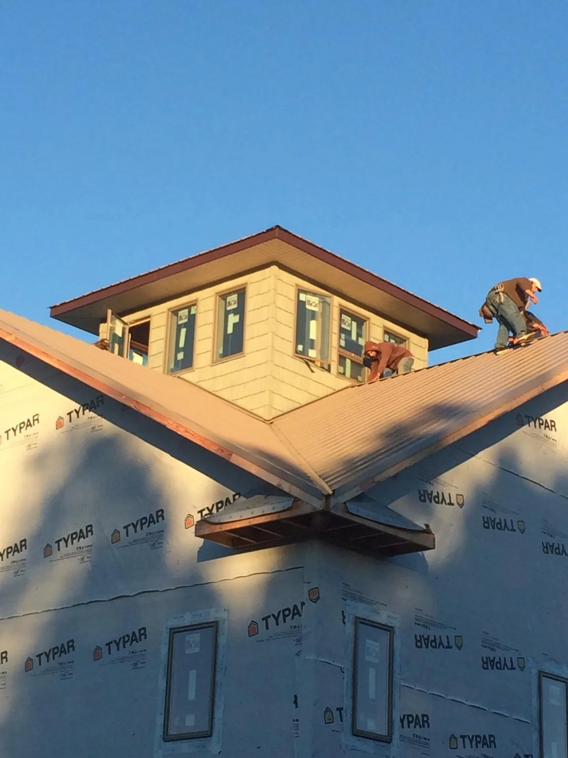 Roofers working around a rooftop cupola on a new metal roof at sunset — Roof Waterproofing in Shelter Island Heights by Roofing Brothers